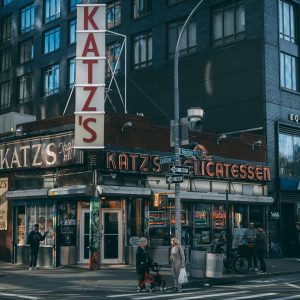 An iconic deli in New York City, Katz's Delicatessen showcases its historic charm with a bustling interior, walls adorned with photos, and a classic pastrami sandwich on a plate.